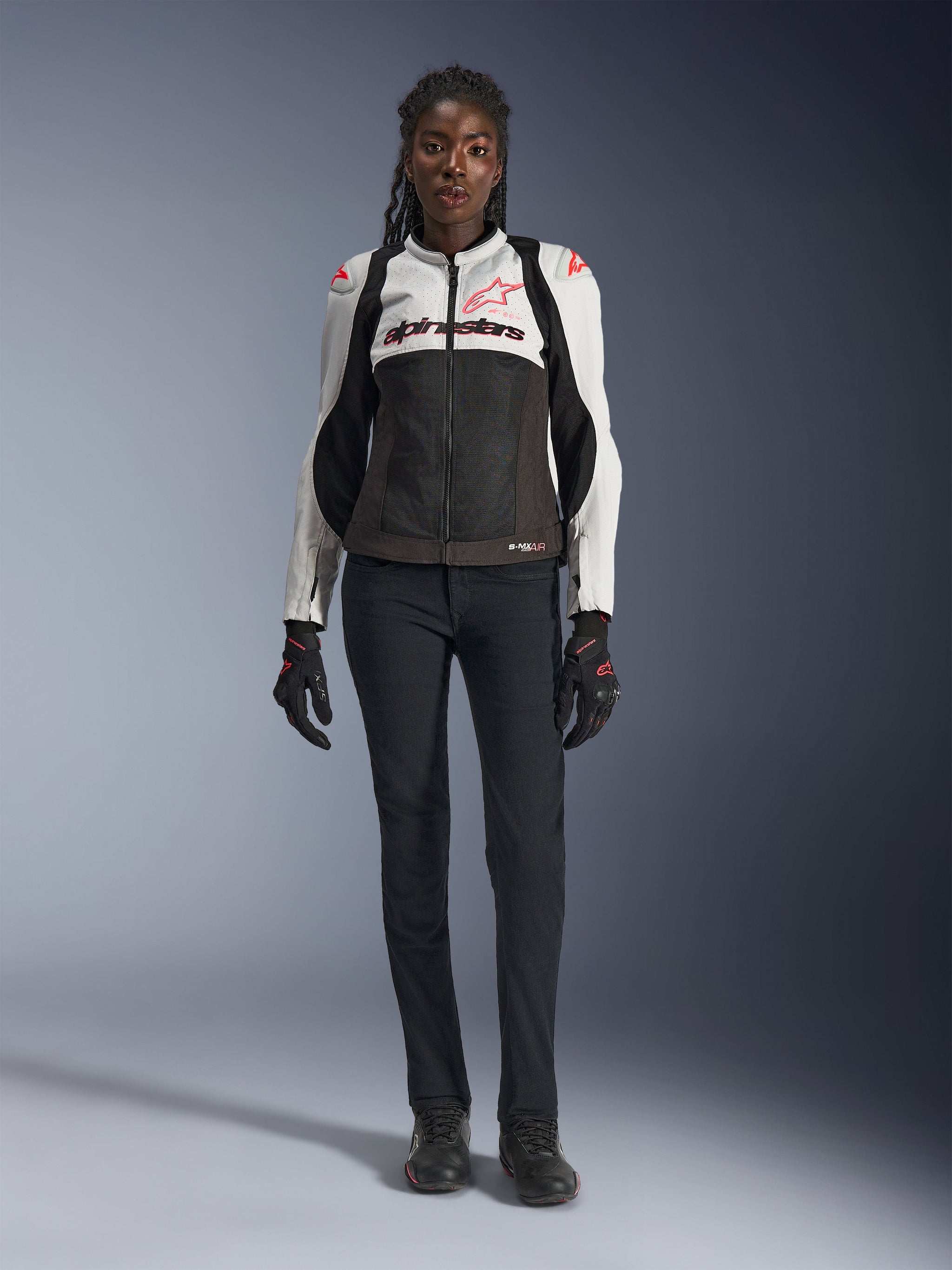 Alpinestars Stella SMX Air Jacket, Ice Gray Black and Coral Fluo, worn by a female model with black riding pants and gloves, featuring a mesh chassis and protective shoulder sliders, sport motorcycle gear for women