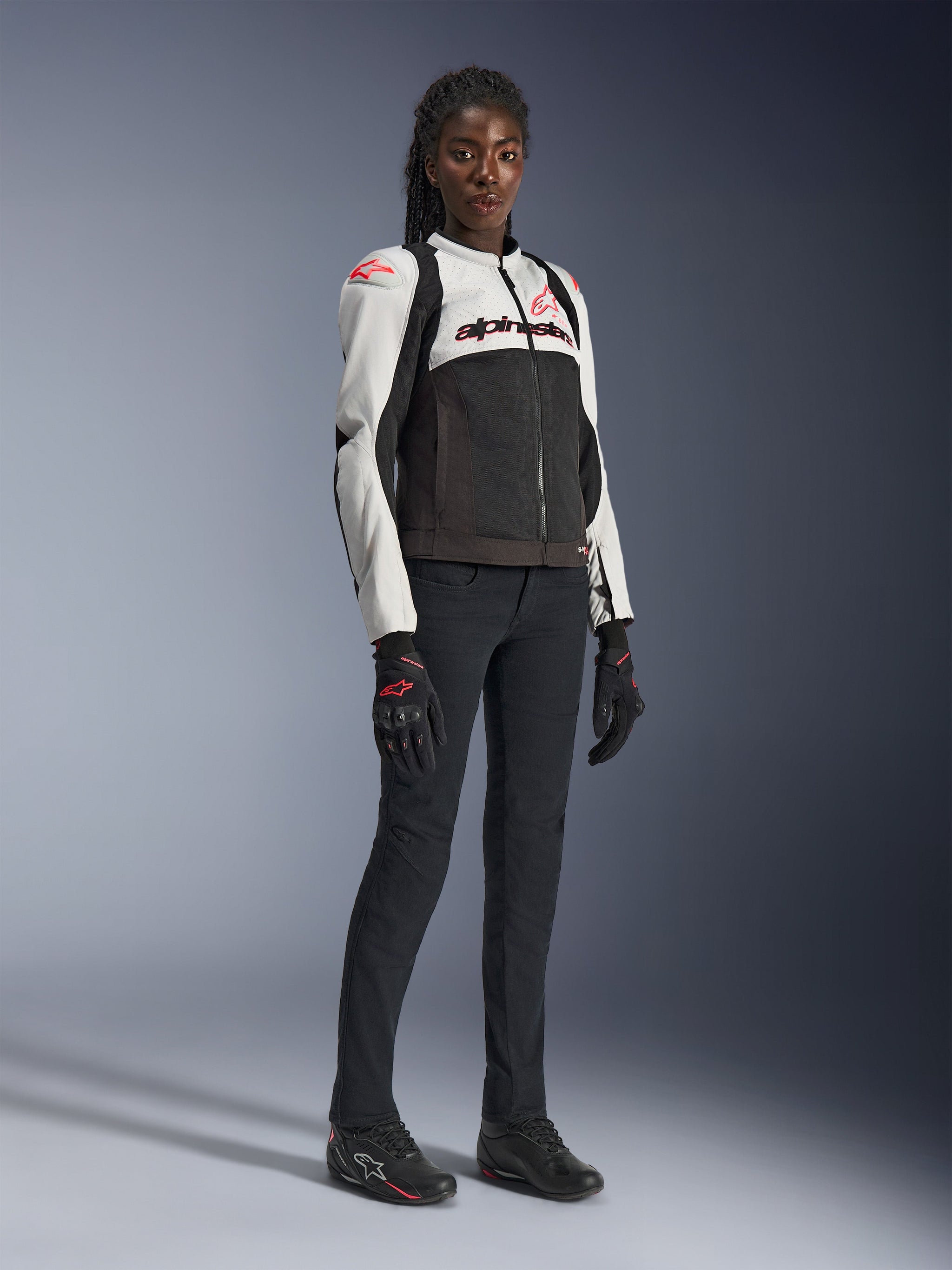 Alpinestars Woman Stella SMX Air Jacket in Ice Gray Black Coral Fluo, worn by a female model with black riding pants and gloves, featuring mesh construction and coral red logos, women's sport motorcycle riding gear
