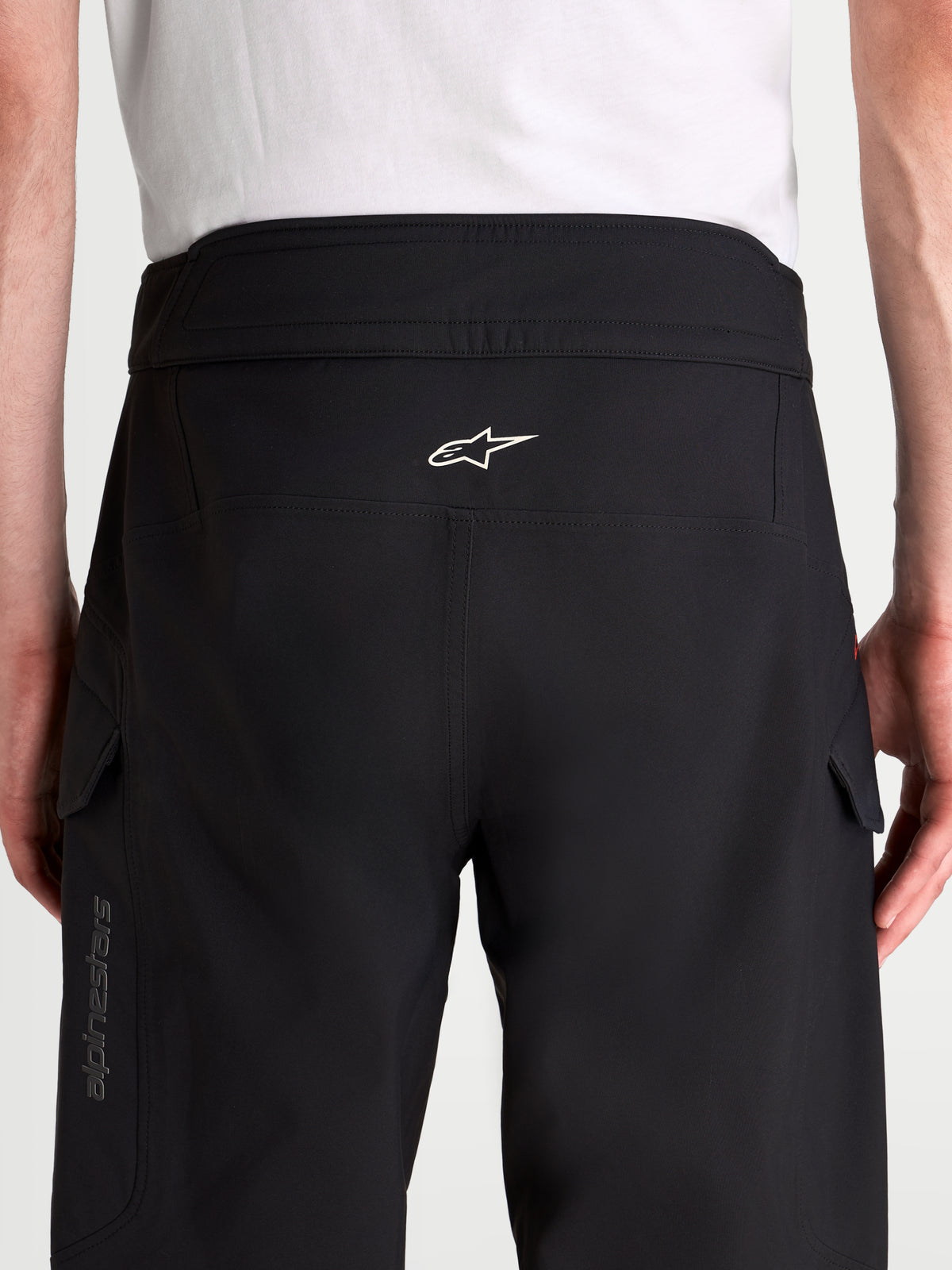 Alpinestars Juggernaut V2 Drystar® Pants, men's waterproof urban motorcycle pants in black, rear view showing high-back waistband, ergonomic seat structure, white Alpinestars logo, and side cargo pockets worn by a model