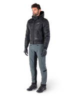 Alpinestars Alden Pants in Urban Gray, worn by a model with a black quilted hooded jacket, gloves, and riding shoes, featuring quilted detailing on the sides and black inner leg panels, streetwear-inspired urban motorcycle gear.