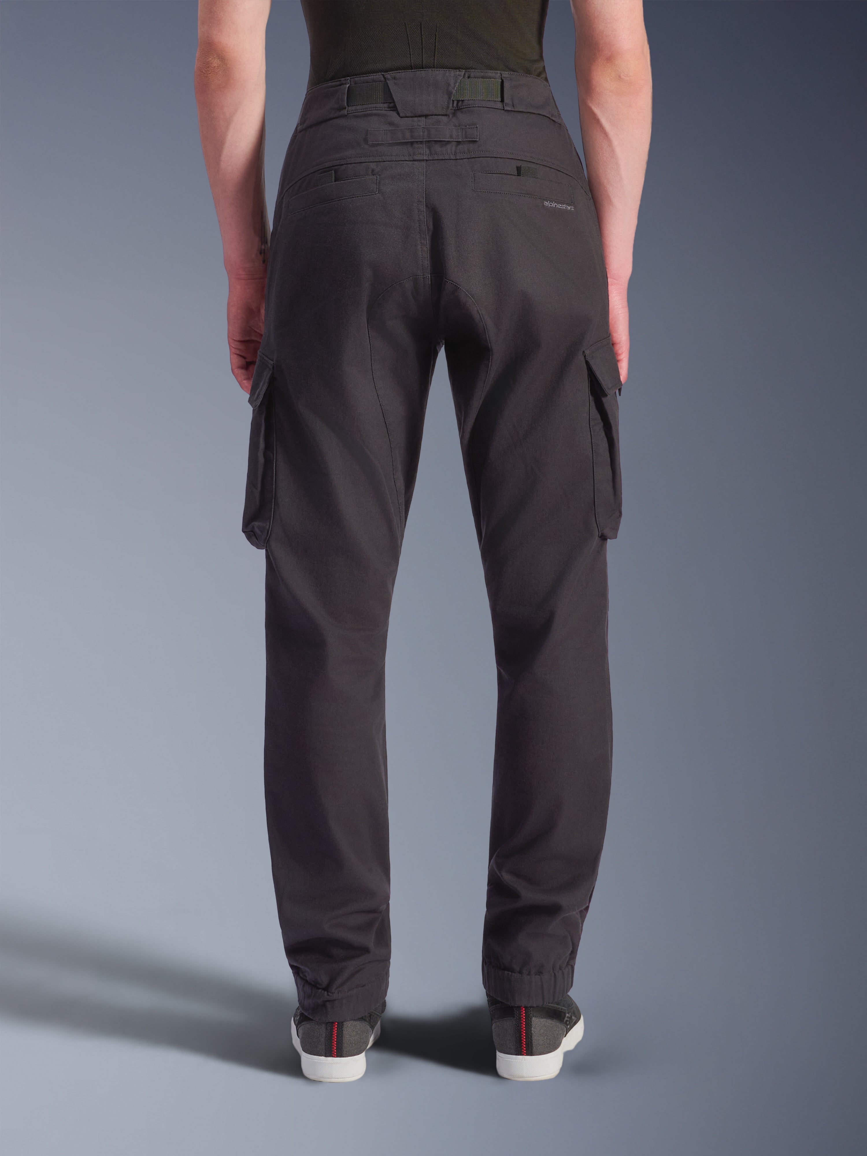 Alpinestars Flex-AST Cargo Pants, pretas, vista traseira de calças técnicas de motociclismo com um corte regular afunilado e bainhas elásticas, apresentando bolsos cargo grandes e marca subtil, concebidas para condução urbana.