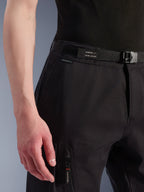 Calças Cargo Alpinestars Flex-AST, pretas, pormenor da zona da cintura e anca, com cinto ajustável integrado com a marca Alpinestars, fecho de fivela e bolso cargo com fecho de correr, tecido técnico elástico para equipamento de motociclismo urbano