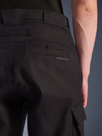 Calças Cargo Alpinestars Flex-AST, calças de motociclismo urbanas, pretas, grande plano da parte traseira e lateral mostrando o bolso traseiro com a marca Alpinestars, aba do bolso cargo lateral e construção em tecido elástico resistente.