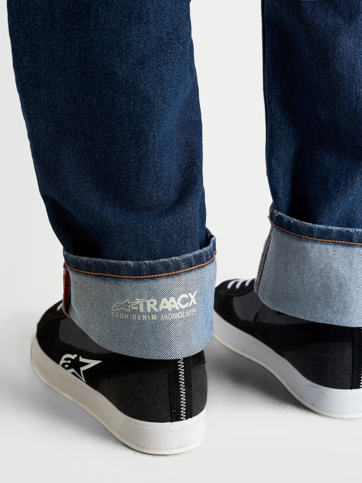 Alpinestars Flex-AST 8 Denim calças de moto, azul médio, vista em plano pormenor da bainha dobrada que mostra a marca técnica de ganga de camada única A-TRAACX e acabamento tipo selvedge