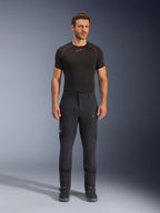 Alpinestars Flex-AST Explorer Pants, calças de motociclista pretas para aventura e touring, homem a usar calças têxteis ajustadas com bolsos cargo com fecho e painéis reforçados, combinadas com uma camada base preta e botas de motociclista, proteção duradoura para condução de aventura