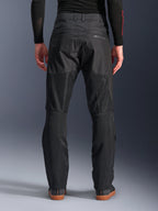 Alpinestars C-1 Air Pants, vista traseira, pretas, calças de motociclismo urbanas em têxtil com grandes painéis de malha técnica na parte de trás das pernas para ventilação, design simples com marca subtil, usadas com uma camada de base preta e sapatilhas de condução casuais.