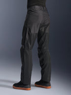 Calças Alpinestars C-1 Air, calças de motociclismo urbanas, pretas, vista traseira mostrando grandes painéis de malha técnica na parte de trás das pernas para ventilação, estilo simples para condução urbana, usadas com ténis pretos casuais.
