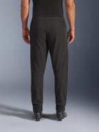Calças Alpinestars Aeroshell Airflow, pretas, vista traseira, com zonas perfuradas a laser nas panturrilhas e painéis de malha, usadas com botas pretas Alpinestars, design softshell leve para desporto e turismo