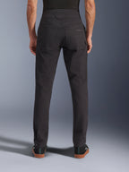 Calças Alpinestars Flex-AST Canvas, calças de motociclismo urbanas, pretas, vista traseira mostrando os bolsos traseiros com logótipo bordado, subida traseira prolongada e costuras ergonómicas nas pernas, usadas com calçado preto casual