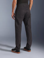 Calças Alpinestars Flex-AST Canvas, pretas, vista traseira mostrando o design clássico de roupa de trabalho com bolsos traseiros grandes, corte ergonómico para condução urbana, usadas com sapatilhas Alpinestars pretas.