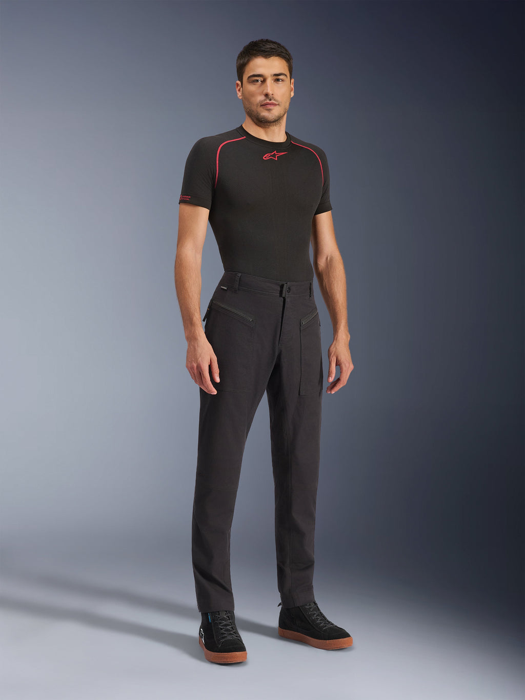 Alpinestars Flex-AST Canvas Pants, calças de motociclismo urbanas, pretas, usadas com uma camada base preta e sapatilhas de cano alto casuais, com bolsos utilitários grandes com fecho de correr e um design inspirado em roupa de trabalho com um corte ergonómico para condução