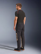Alpinestars Flex-AST Canvas Pants, Black Aluminum, calças de motociclismo urbanas, painéis laterais beges com a marca Alpinestars, usadas com camada base preta e ténis, vista traseira com estilo inspirado em vestuário de trabalho e corte ergonómico para moto.
