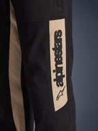 Calças Alpinestars Flex-AST Canvas, detalhe em grande plano da lateral da perna, pretas com painel de realce em tom alumínio, com logótipo Alpinestars vertical e ícone de estrela em preto, sarja de policotão durável para condução urbana de motociclo
