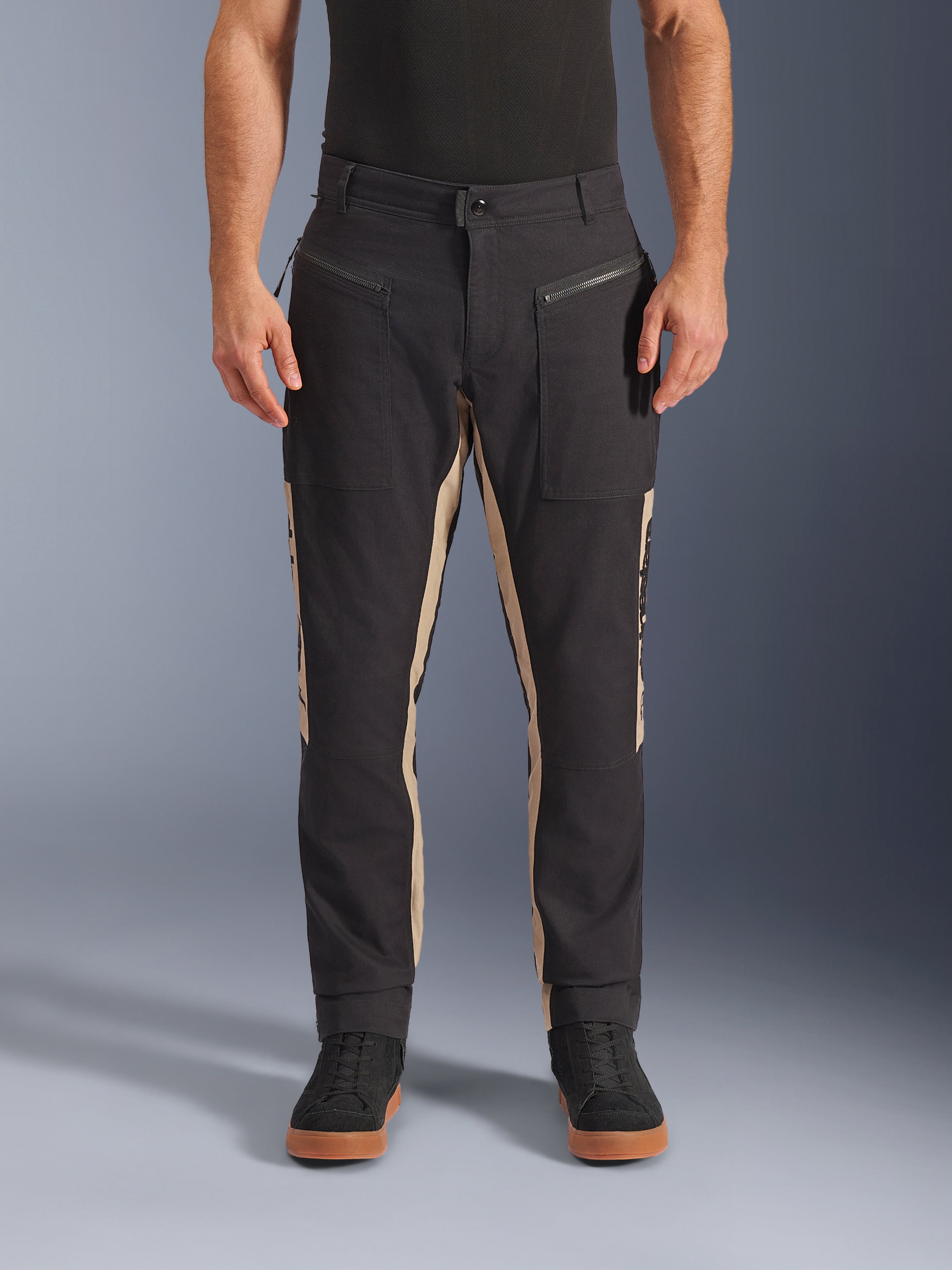 Calças Alpinestars Flex-AST Canvas, calças de motociclismo urbanas, Preto e Alumínio, design inspirado em vestuário de trabalho clássico, bolsos frontais com fecho de correr, corte ergonómico para moto, usadas com t-shirt preta e ténis pretos casuais, estilo urbano utilitário
