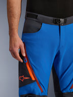 Alpinestars Maxdura Dual Pants in Royal Blue and Deep Gray, close-up view of the waistband with magnetic buckle, zippered cargo pocket with orange detailing and red Alpinestars logo, technical adventure motorcycle riding gear