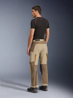 Alpinestars Maxdura Dual Pants, calças de condução de aventura e dual-sport, cor Walnut Aluminum, vista traseira num modelo com camisola interior preta e botas de condução, com construção multi-painel, aberturas traseiras com fecho e reforços sobrepostos.