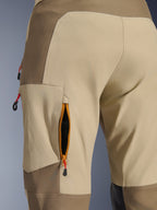 Alpinestars Maxdura Dual Pants em Walnut Aluminum, detalhe em grande plano de abertura de ventilação na coxa com fecho, rebordo cor-de-laranja e malha preta, tecido de poliamida elástica resistente em bege e castanho com puxadores vermelhos