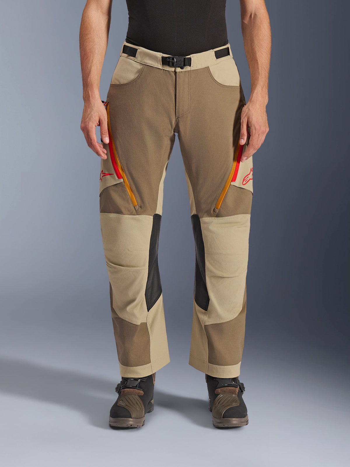 Alpinestars Maxdura Dual Pants, Walnut Aluminum, calças de motociclismo de aventura com aberturas de ventilação nas coxas com fechos vermelhos e cor de laranja, painéis interiores nos joelhos em pele preta, usadas com uma camada base preta e botas robustas, design durável em vários tons para condução dual-sport