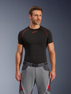 Calças Alpinestars Maxdura Dual, cinzento escuro e cinzento profundo com detalhes vermelhos, usadas com uma camisola base layer preta com costuras vermelhas, corte atlético com cinto de fivela magnética integrado, equipamento de motociclismo de aventura durável