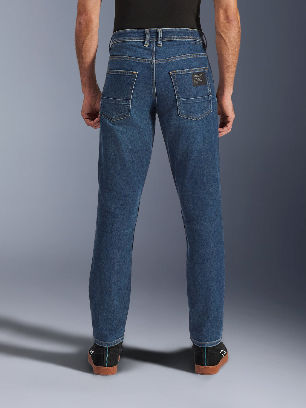 Alpinestars Flex-AST 5 Denim Pants, calças de ganga para motociclismo urbano, azul índigo lavado, vista traseira mostrando o corte afunilado e bolsos traseiros com patch da marca, estilo casual