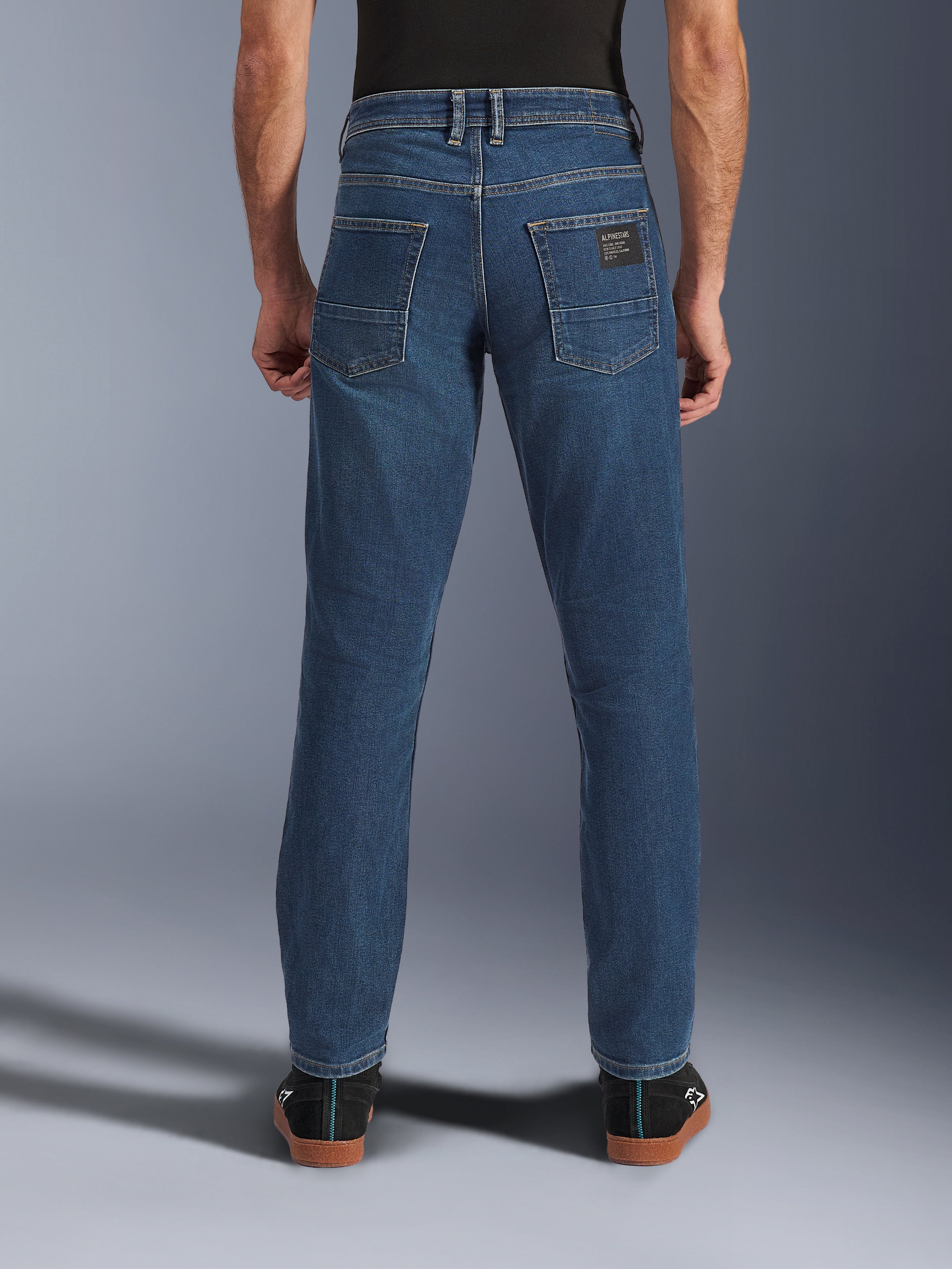 Alpinestars Flex-AST 5 Denim Pants, calças de ganga para motociclismo urbano, azul índigo lavado, vista traseira mostrando o corte afunilado e bolsos traseiros com patch da marca, estilo casual