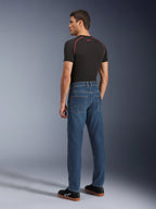 Alpinestars Flex-AST 5 Denim Pants, Indigo Washed, vista traseira do modelo a usar as calças, calças de ganga urbanas para motociclismo, corte afunilado com ganga elástica de camada única, combinadas com uma t-shirt preta e sapatilhas pretas