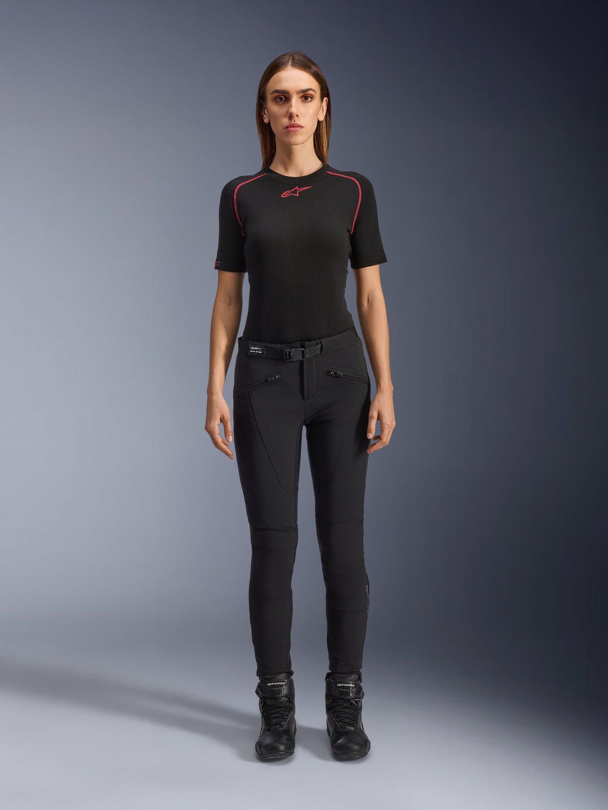 Alpinestars Alamosa Women Pants, calças de motociclismo pretas de corte slim, apresentadas numa modelo virada para a frente, com bolsos frontais com fecho de correr e um cinto integrado na cintura, estilo minimalista inspirado no streetwear para condução urbana
