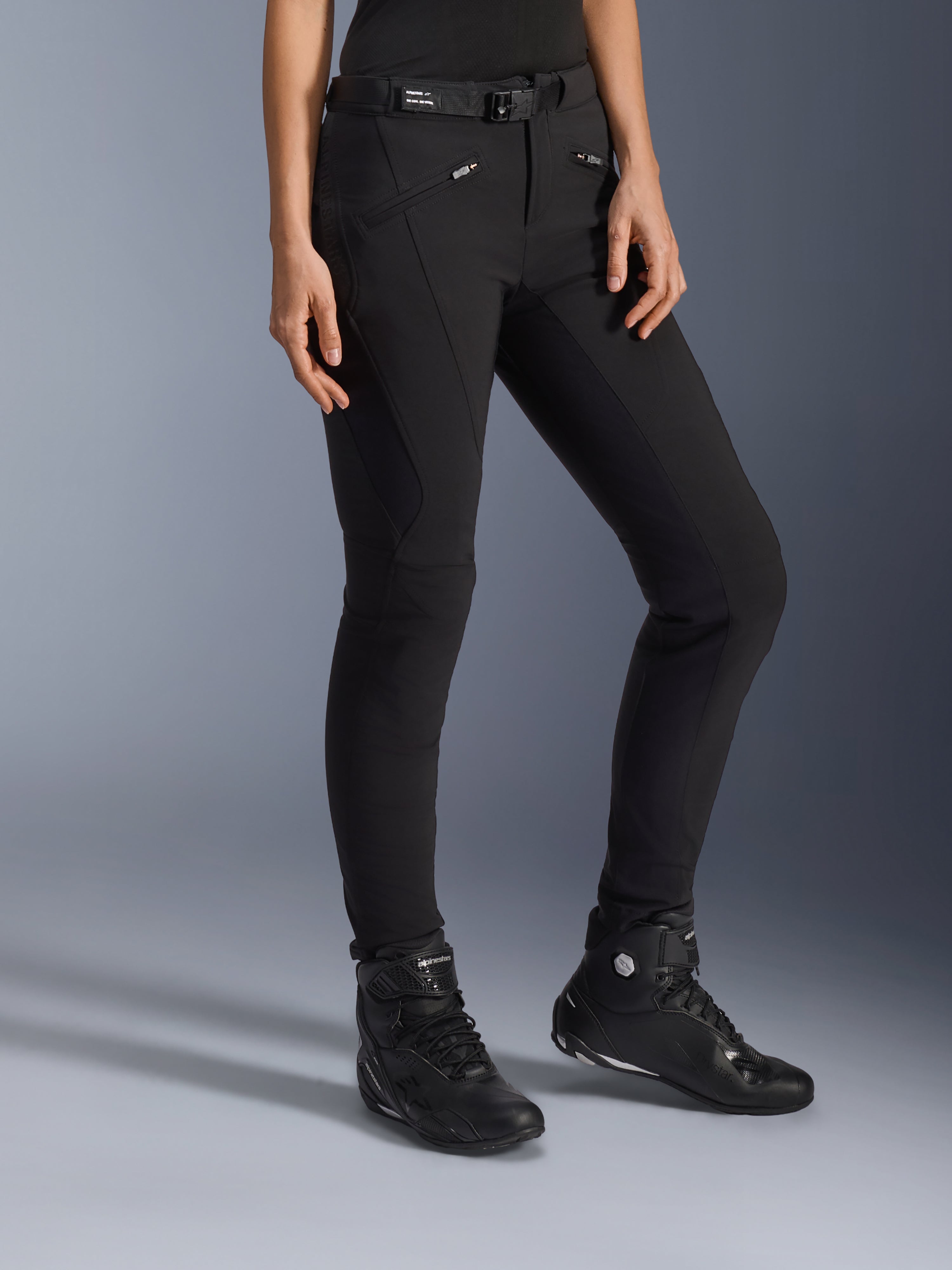 Alpinestars Alamosa Women Pants, calças de motociclismo urbanas pretas, design slim-fit com bolsos com fecho de correr e cinto integrado na cintura, combinadas com sapatos de condução pretos de cano alto