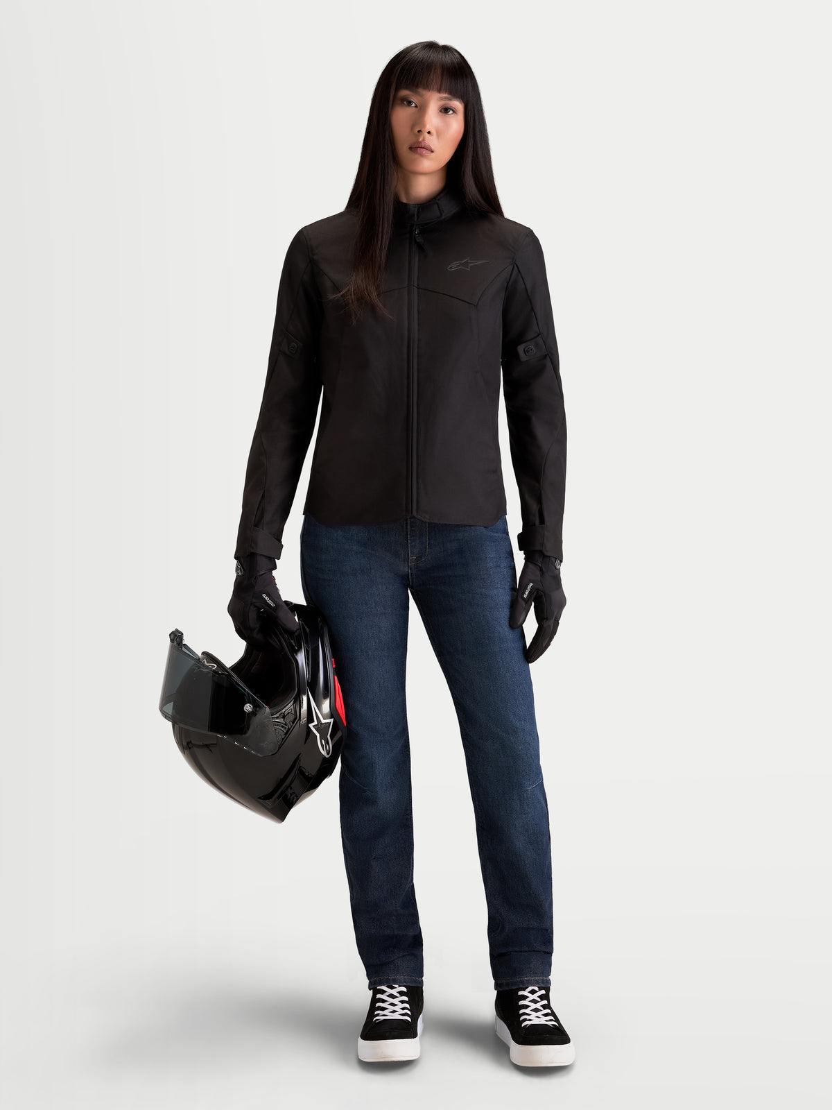 Alpinestars Stella Flex-AST 7 Denim Calças, calças de ganga de moto urbanas para mulher em azul escuro, usadas por uma modelo a segurar um capacete e um blusão a combinar