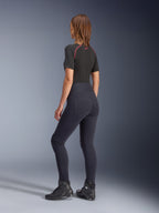 Leggings Stella Flex-Ast Femininas Alpinestars, pretas, vista traseira mostrando o corte de cintura alta e os bolsos traseiros, usadas com uma camada de base de manga curta preta com detalhes vermelhos e sapatos de motociclismo pretos, equipamento de motociclismo urbano contemporâneo
