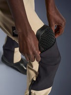 Calças Alpinestars Woman Stella Flex-AST Explorer, calças de motociclismo de aventura, Aluminum Black e Tan, grande plano mostrando o bolso exterior do protetor de joelho com a proteção preta Nucleon Flex Plus em favo de mel a ser ajustada, construção têxtil durável para condução em clima quente.