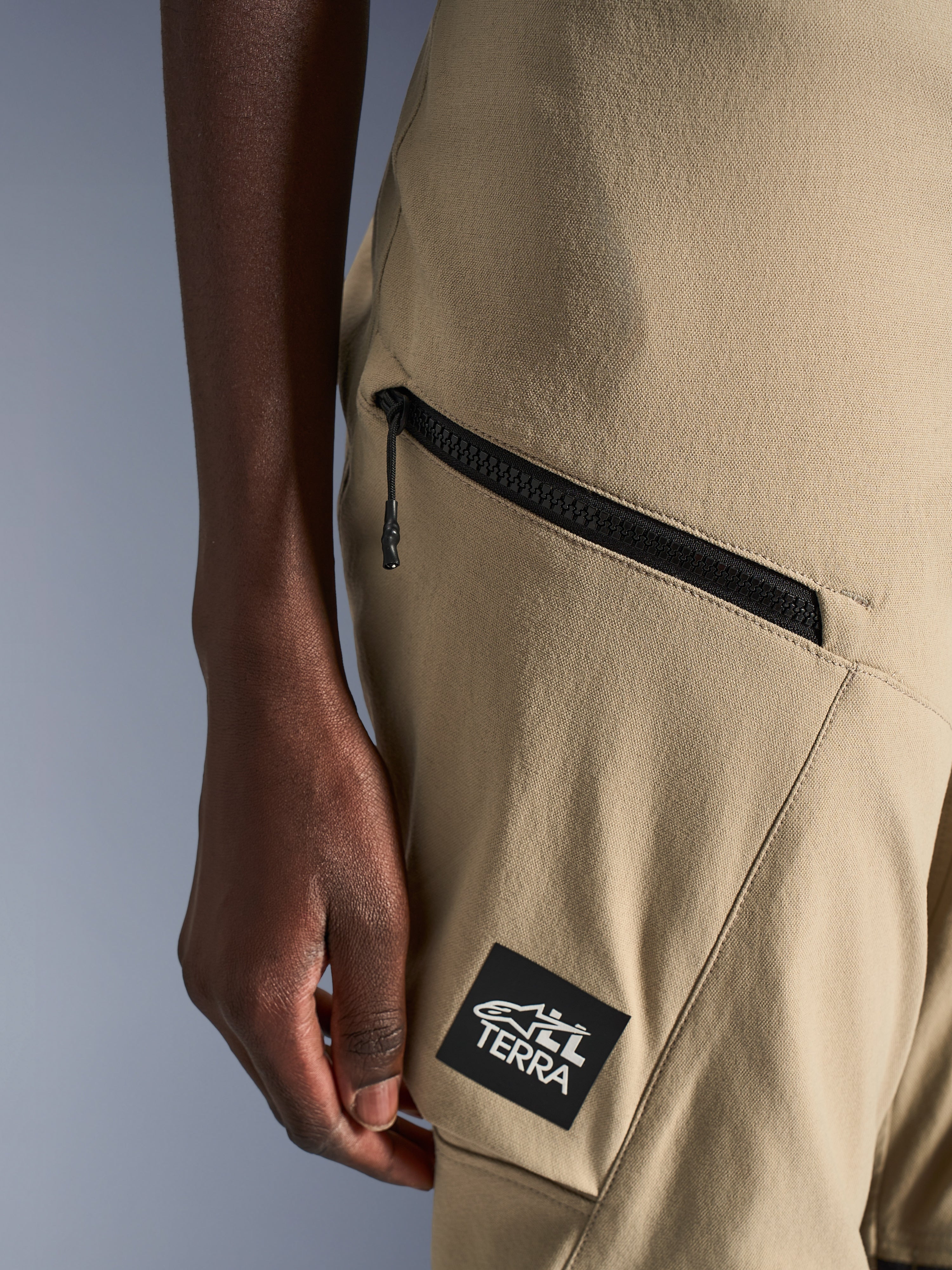 Alpinestars Stella Flex-AST Explorer Pants, calças de motociclista para mulher, cor areia, pormenor de bolso cargo com fecho de correr e patch preto com logótipo ALL TERRA, construção têxtil ripstop durável para condução de aventura