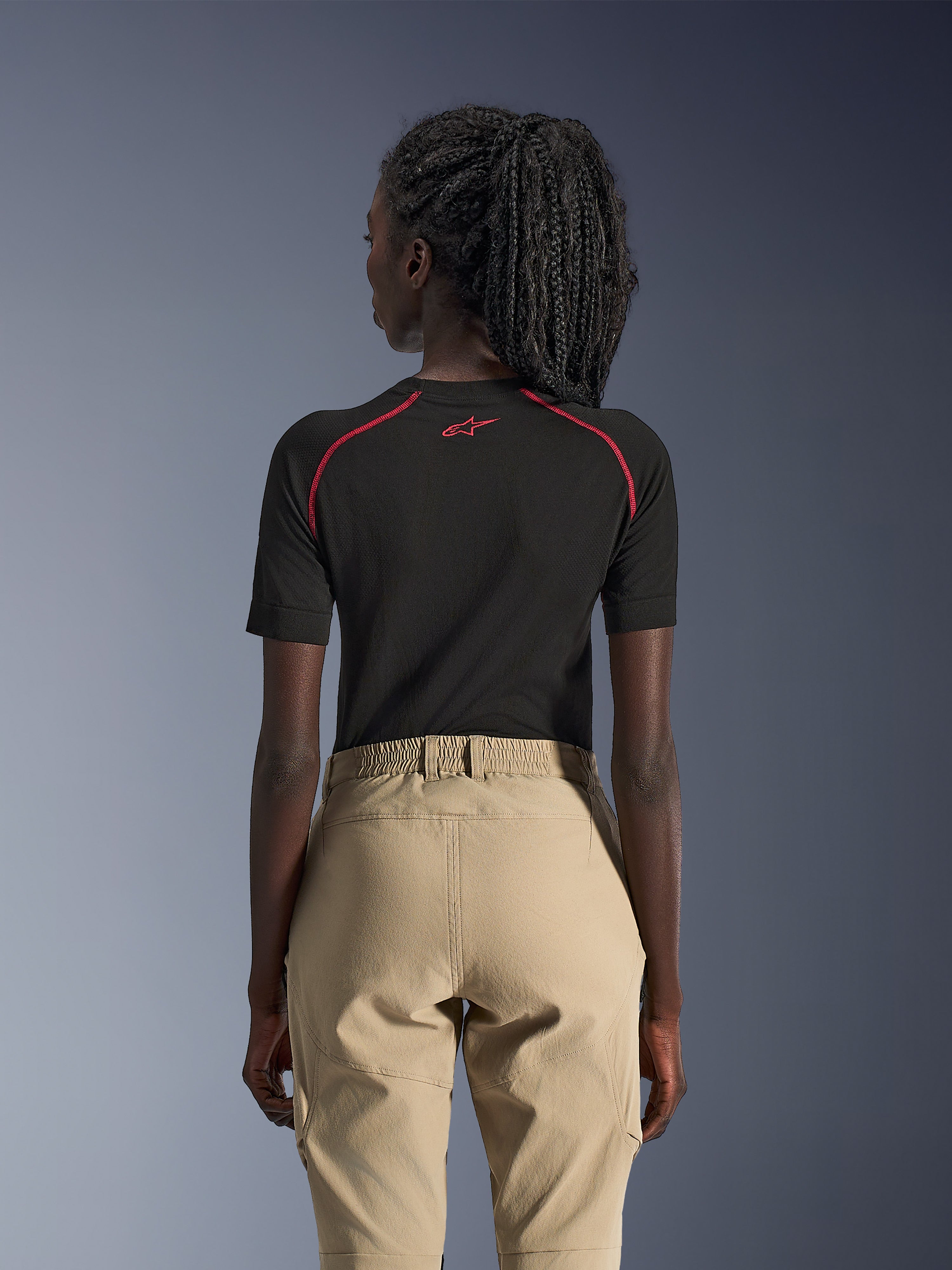 Alpinestars Stella Flex-AST Explorer Pants para Mulher, cor Areia, calças de motociclismo de aventura, vista traseira, usadas com uma camisola interior preta de manga curta com detalhes vermelhos, apresenta cintura elástica e construção em têxtil resistente