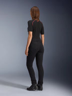 Alpinestars Leggings Banshee Femininas, pretas, vista traseira que mostra o ajuste anatómico elástico e os bolsos traseiros, usadas com um top preto de manga curta e botas de motociclismo, equipamento de motociclismo urbano elegante para mulher