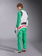 Fato Alpinestars KMX-9 V3 Graphic 6, fato de karting, branco, verde e vermelho, modelo visto de costas lateralmente, com mangas e painéis inferiores verdes, tronco superior branco com detalhes de salpicos pretos, logótipo Alpinestars em vermelho na zona lombar, acompanhado por sapatos de karting brancos e verdes a condizer