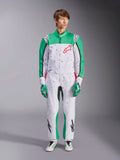 Fato Alpinestars KMX-9 V3 Graphic 6, branco, verde e vermelho, fato de karting de uma peça com um padrão gráfico de salpicos pretos, painéis verdes nas mangas e pernas, logótipo Alpinestars vermelho no peito, usado com luvas e sapatos de corrida a condizer