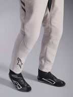 Fato Alpinestars GP Race V3 FIA, fato de automobilismo Silver Anthracite, detalhe da parte inferior das pernas e botas de corrida pretas, com o logótipo Astars preto na perna, equipamento profissional de desporto motorizado com punhos canelados