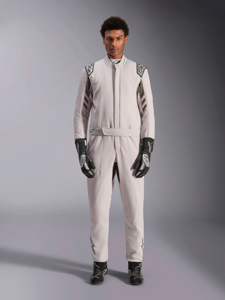 Macacão Alpinestars GP Race V3 FIA em Silver Anthracite, fato de automobilismo de uma peça usado por um modelo, com dragonas e detalhes em cinzento escuro, combinado com luvas e botas de corrida pretas, equipamento de proteção profissional para desportos motorizados