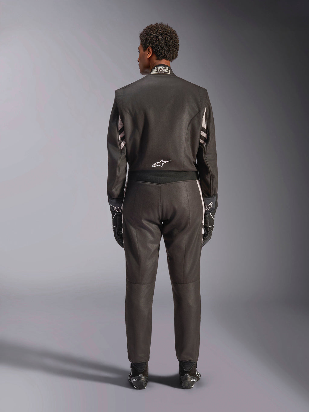 Alpinestars GP Race V3 Suit FIA, Vista traseira, preto e prateado, fato de automobilismo profissional com construção em aramida de duas camadas e painéis elásticos, usado com luvas e botas de corrida a condizer