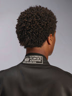 Alpinestars GP Race V3 Suit FIA, fato de corrida preto, grande plano da gola traseira, com patch de certificação FIA 8856-2018, vista detalhada da homologação de segurança e logótipo Alpinestars, equipamento de desporto motorizado de alta performance