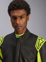 Primeiro plano de um modelo a usar o fato Alpinestars GP Race V3 Suit FIA em Preto e Amarelo Fluo, com ombreiras de extração amarelas nos ombros com logótipos de estrela, design de gola alta, equipamento profissional de automobilismo.