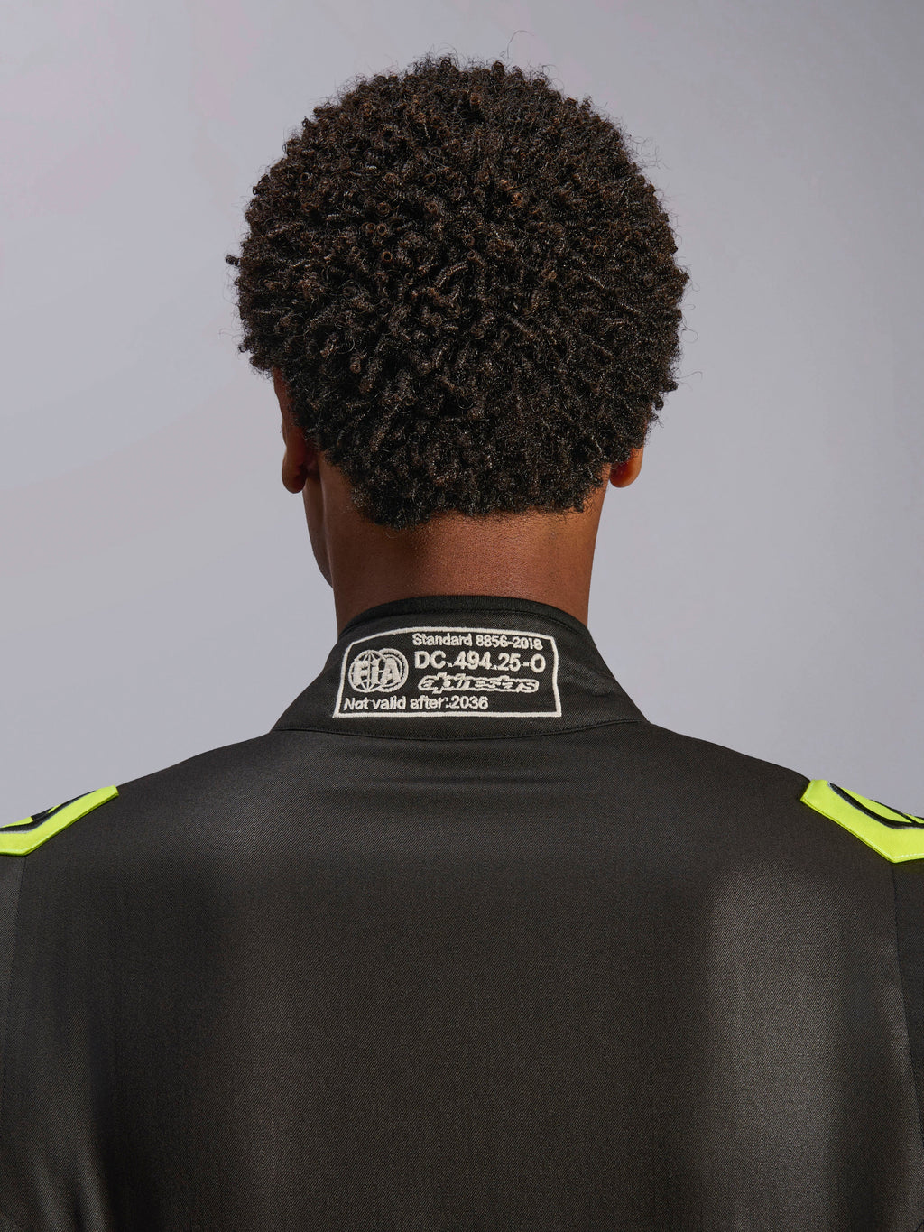Fato Alpinestars GP Race V3 FIA, preto e amarelo fluorescente, grande plano da gola traseira com a etiqueta de certificação FIA 8856-2018, fato de corrida automóvel profissional
