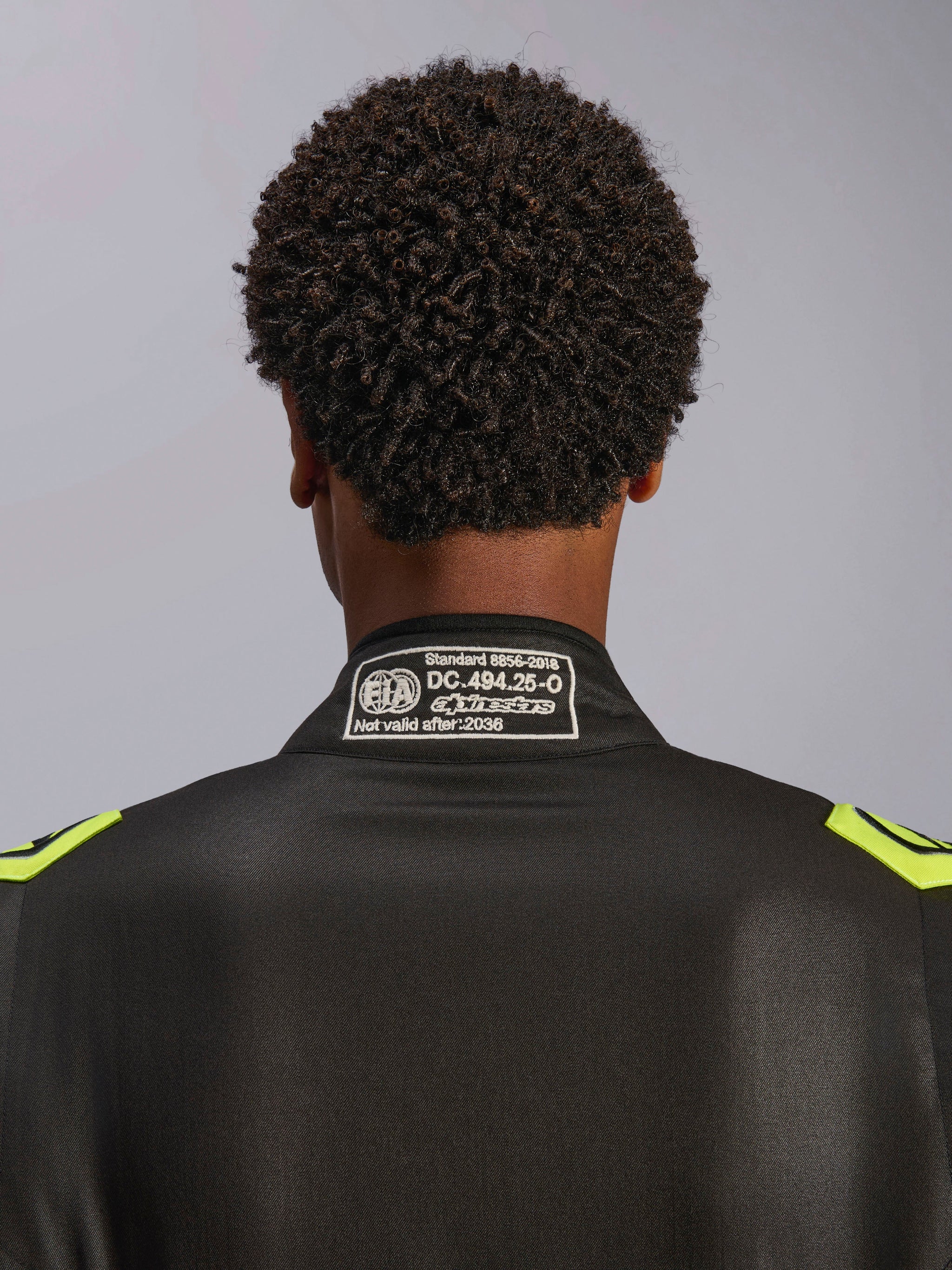 Fato Alpinestars GP Race V3 FIA, preto e amarelo fluorescente, grande plano da gola traseira com a etiqueta de certificação FIA 8856-2018, fato de corrida automóvel profissional