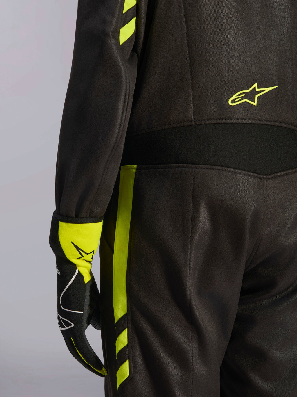 Alpinestars GP Race V3 Suit FIA, preto e amarelo fluo, detalhe em grande plano da cintura e da lateral da perna, com painéis elásticos de aramida e luva de corrida a condizer, equipamento profissional de automobilismo