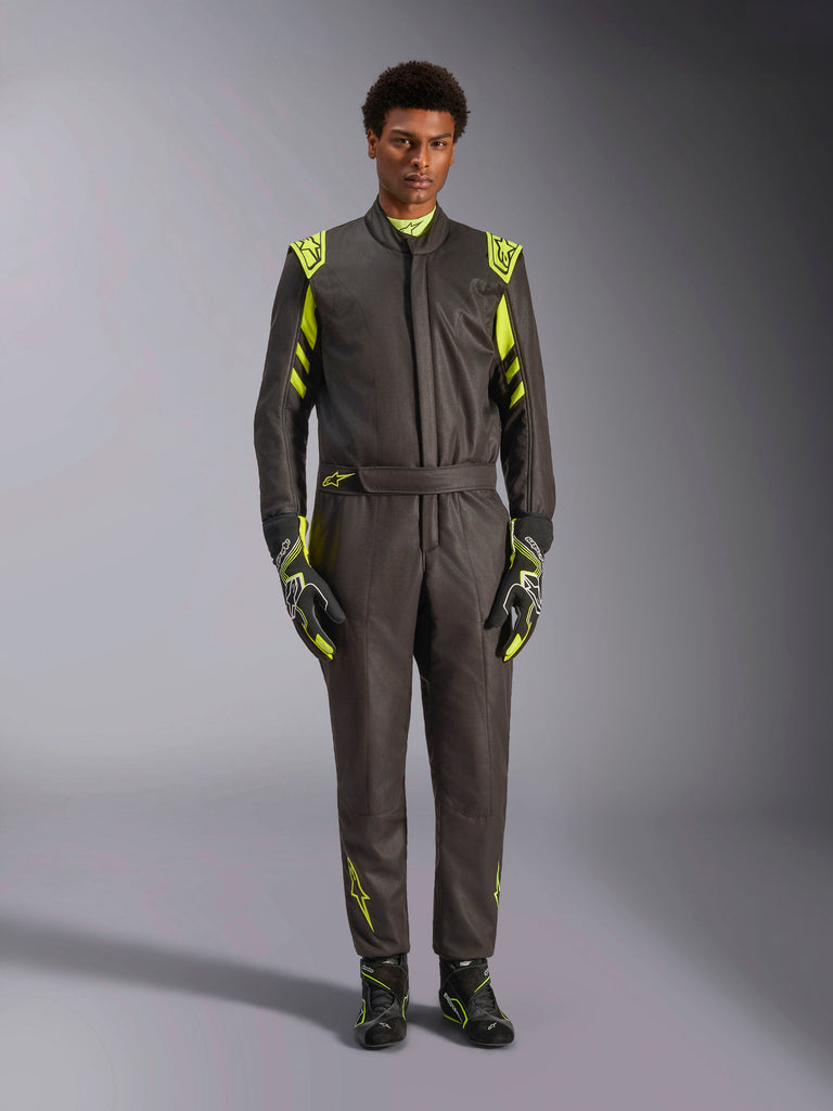 Alpinestars GP Race V3 Suit FIA, fato de automobilismo, preto e amarelo fluorescente, usado por um modelo com luvas e botas de corrida a condizer, com detalhes em amarelo vibrante nos ombros, cintura e mangas, equipamento profissional de desportos motorizados