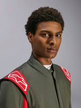 Alpinestars GP Race V3 Suit FIA, fato de automobilismo, antracite e vermelho, grande plano do tronco superior e cabeça, apresentando dragonas vermelhas nos ombros com o logótipo Alpinestars branco, gola alta e material de sarja cinzenta