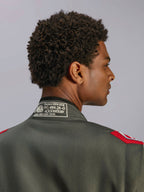 Alpinestars GP Race V3 Suit FIA, fato de corrida em antracite e vermelho, grande plano da parte de trás da gola com etiqueta de certificação FIA 8856-2018 e dragonas vermelhas nos ombros, detalhe de vestuário de automobilismo profissional
