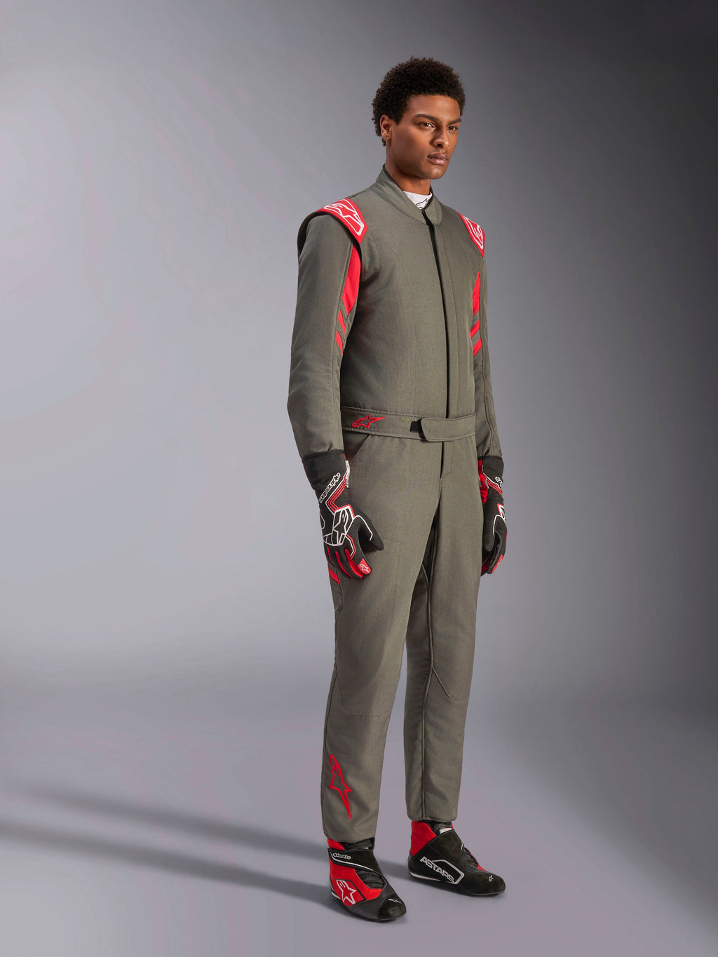 Fato Alpinestars GP Race V3 FIA, fato de automobilismo Antracite Vermelho, usado com luvas e botas de competição a condizer, com ombreiras vermelhas e logótipos da marca, design técnico elegante de duas camadas para desportos motorizados