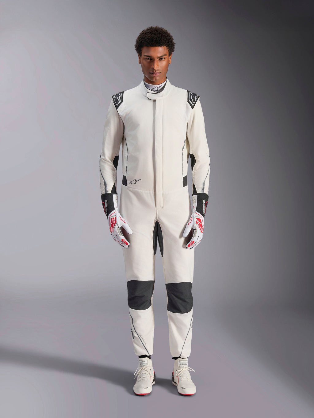 Alpinestars Hypertech V3 Suit, Professional Auto Racing Suit, White Black and Silver, worn by model with red and white gloves and matching white racing shoes, featuring black contrast panels and Alpinestars logos, athletic slim fit design