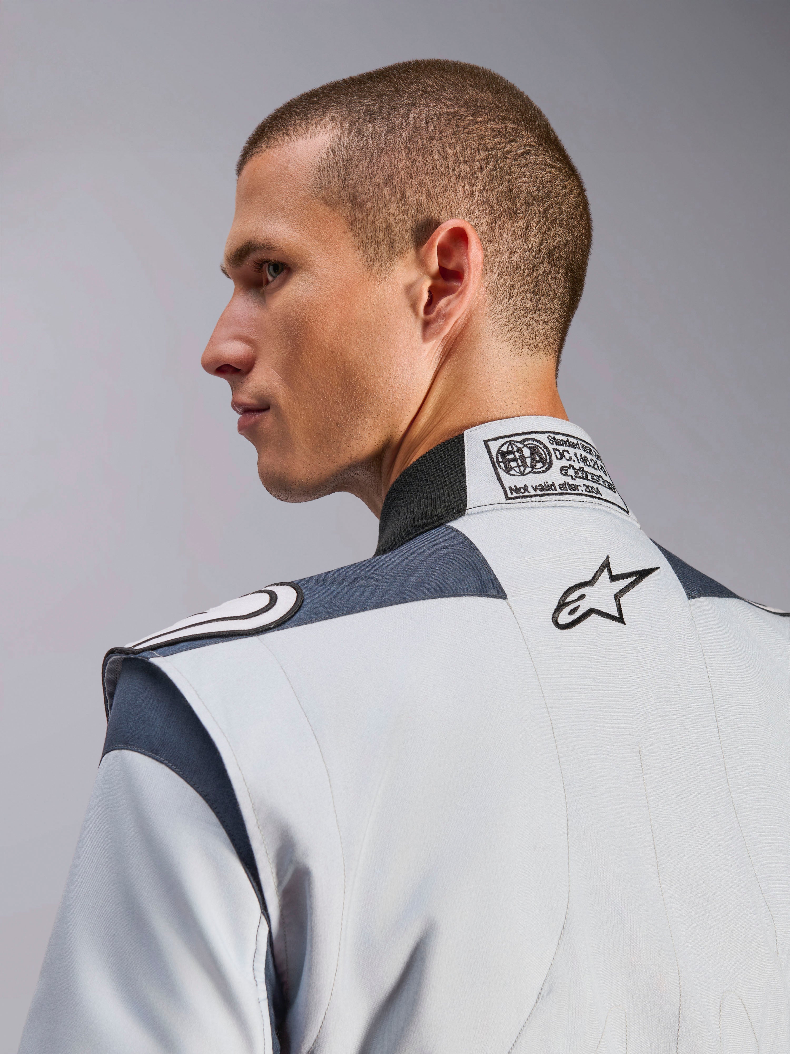 Alpinestars GP Pro Comp V2, macacão de corrida para homem, prateado e cinzento, com etiqueta FIA e logótipo bordado.